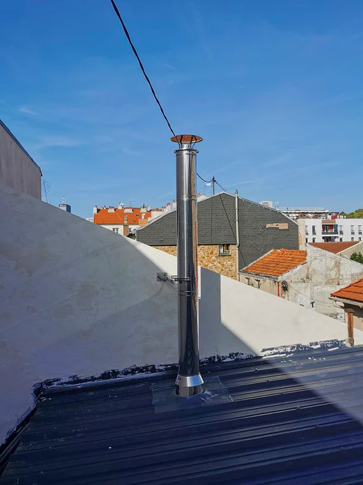 Façade extérieure d'un bâtiment résidentiel, installation d'un conduit de fumée en inox double paroi fixé en applique