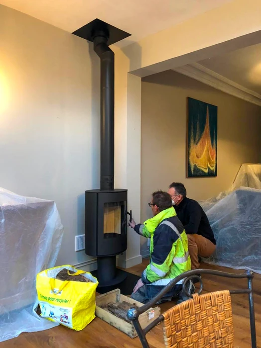 Poêle à bois design contemporain, carrosserie bicolore blanc et noir, vitre frontale avec feu actif visible, stockage de bûches intégré en partie basse