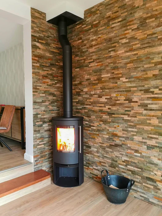 Poêle à bois design contemporain, carrosserie bicolore blanc et noir, vitre frontale avec feu actif visible, stockage de bûches intégré en partie basse