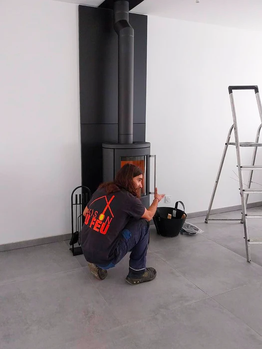 Poêle à bois design contemporain, carrosserie bicolore blanc et noir, vitre frontale avec feu actif visible, stockage de bûches intégré en partie basse