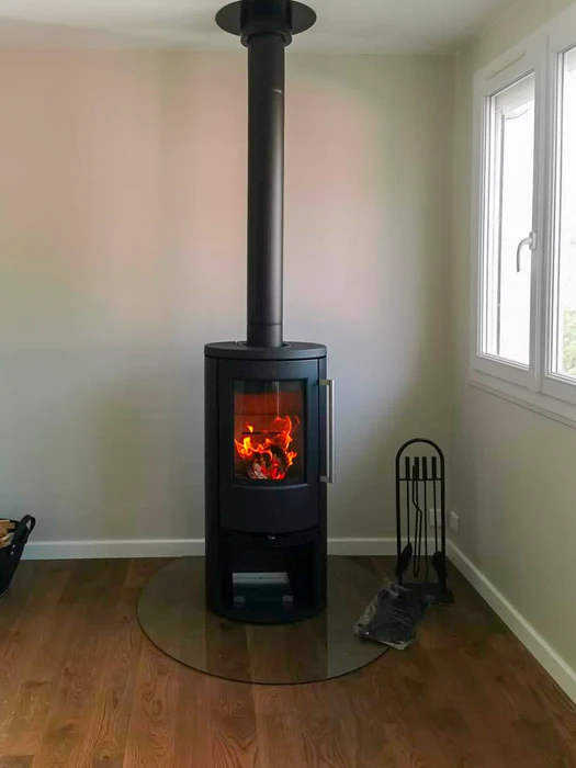 Poêle à bois design contemporain, carrosserie bicolore blanc et noir, vitre frontale avec feu actif visible, stockage de bûches intégré en partie basse