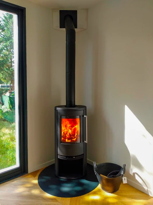 Poêle à bois design contemporain, carrosserie bicolore blanc et noir, vitre frontale avec feu actif visible, stockage de bûches intégré en partie basse