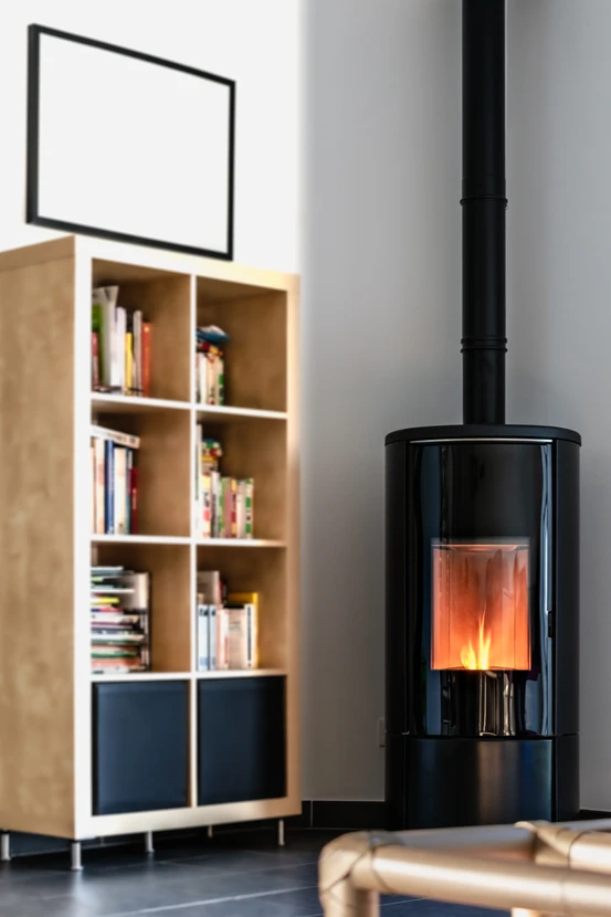 Intérieur domestique avec poêle à bois en fonte noire allumé, flammes visibles derrière la vitre