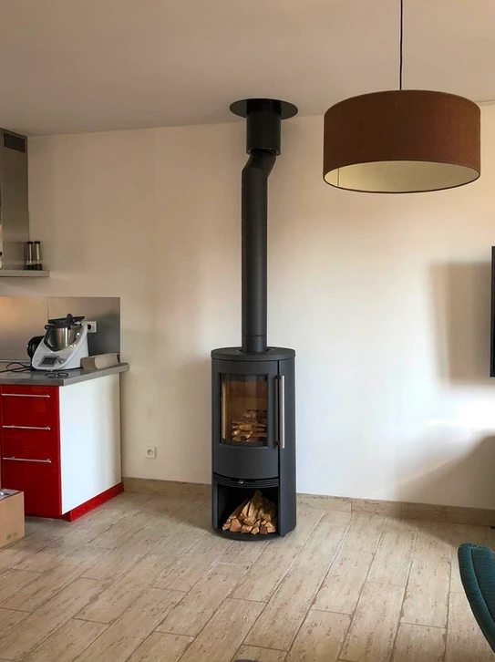 Intérieur résidentiel avec poêle à bois moderne noir en fonctionnement, flammes visibles à travers la vitre